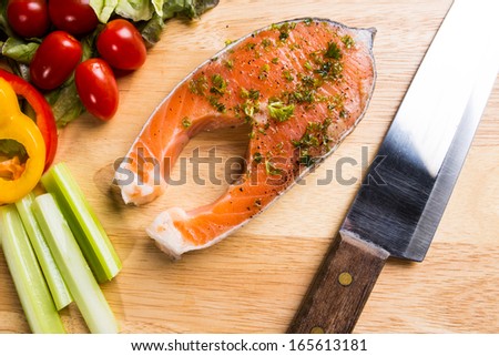 Raw Salmon steak  on cutting board  with knife  and vegetables.