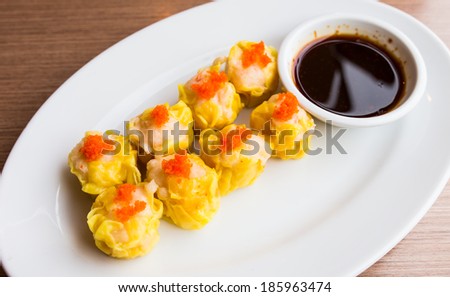 Steamed dumplings made from pork and prawn with fish egg in plate with sauce, timsum in plate.