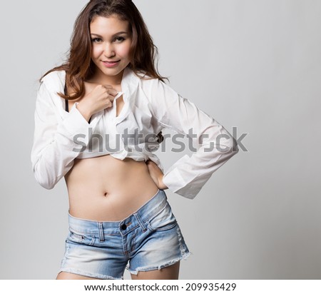 Beautiful brunette girl in jeans and white shirt smiling on white background