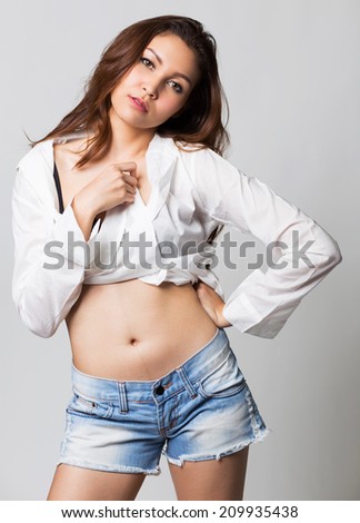 Beautiful brunette girl in jeans and white shirt smiling on white background