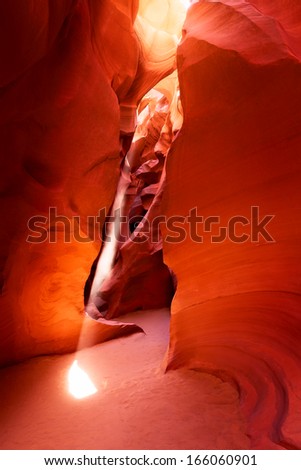 A ray of sunlight sneaks into a desert slot canyon in the American South West setting the walls aglow.