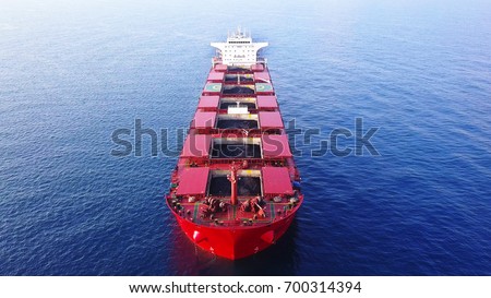 Large red Bulk ship / A coal ship docking outside big power station docking with Open storage