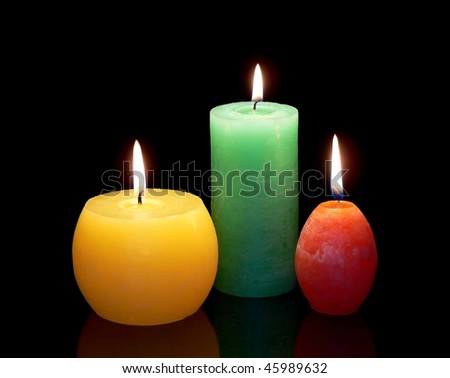 three color burning candles isolated on black