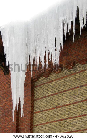 Long, big and dangerous icicles on a brick house roof