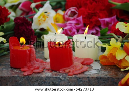 four burning candles on cut flowers background