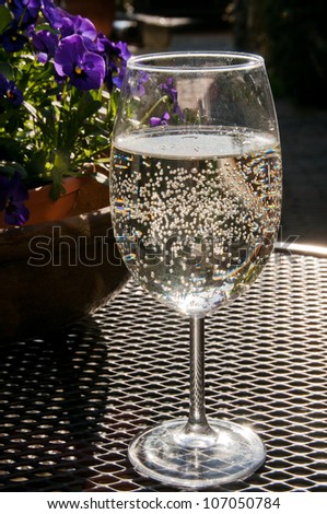 Glass of sparkling white wine on a terrace in the evening sun