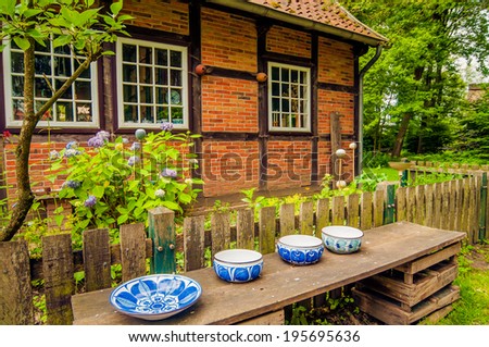 Ceramic blue painted bowls on a wooden shelf in front of an old German characteristic house