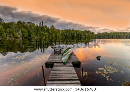 Green Canoe and Chairs on a Dock Next to a Lake at Sunset - Haliburton Highlands, Ontario, Canada
