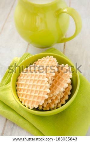 Waffles in the green ceramic bowl with jug of milk on the old retro kitchen table