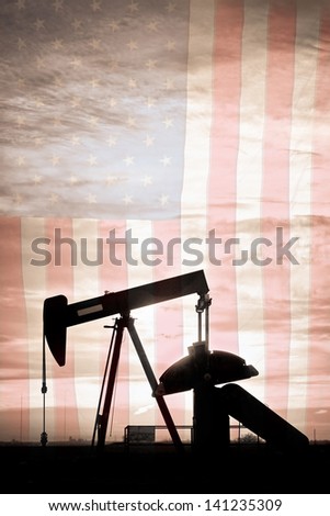 Portrait image of a oil well pumpjack wiith early morning light and American USA red White and Blue Flag background. A Pumpjack is the overground drive for a reciprocating piston pump in an oil well.
