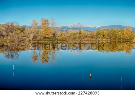 Scenic autumn season view of the twin Peaks, Mt meeker 13,911 ft and Longs Peak  14,256 ft  with mirror like reflections from Golden Ponds in Longmont Colorado, Boulder County.