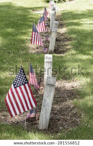 Military Veteran cemetery tombstones view with United States of America red, white and blue flags.