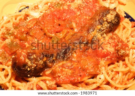 Bed of Spaghetti pasta with a red sauce and sausage link.