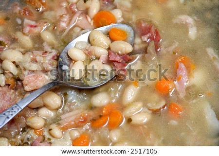 Spoon in a Navy bean soup with ham and carrots. soup,beans,pinto,navy