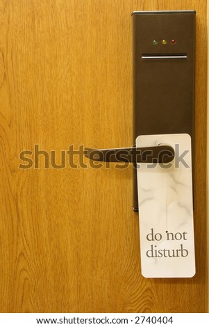 Hotel wood door with a Do not disturb sign hanging on it.