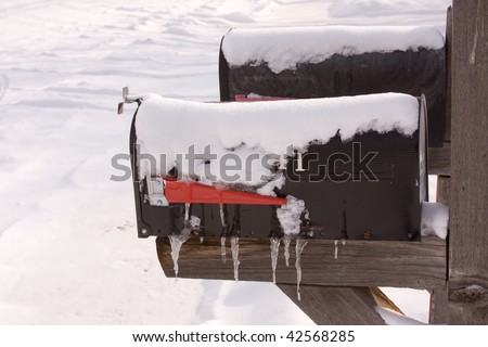 Two black mail boxes covered with snow and ice sickles.  Snow Background.