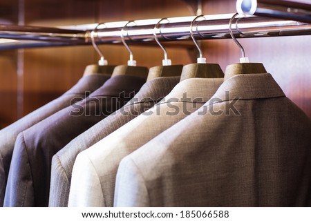 Row of men\'s suit jackets hanging in closet