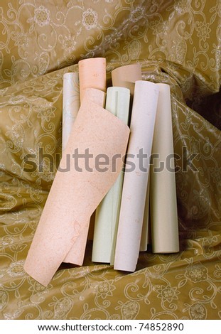 Rolls of wallpaper ready to serves your ideas display on the brown fabric background