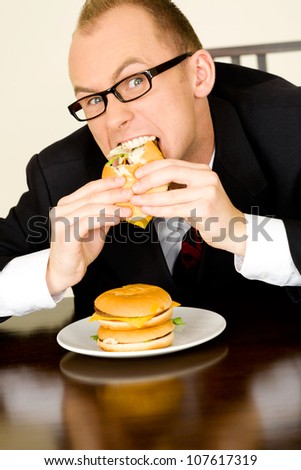 Young businessman during his lunch time eating a hamburger