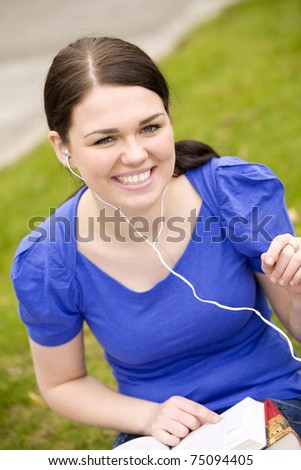 Young cheerful woman reading book and listening to music