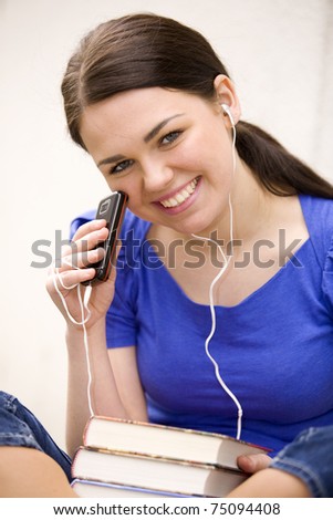 Young cheerful woman reading book and listening to music