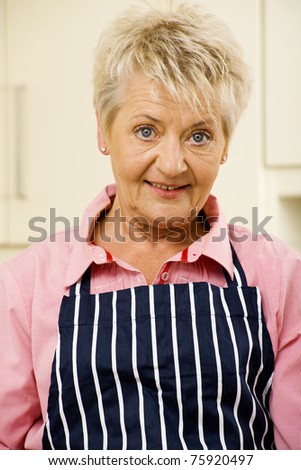 Senior woman portrait wearing an apron in her kitchen