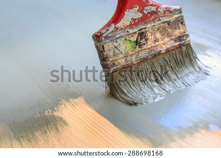 Old used paint brush painting wood background. Focused on brush only.  Background painted.