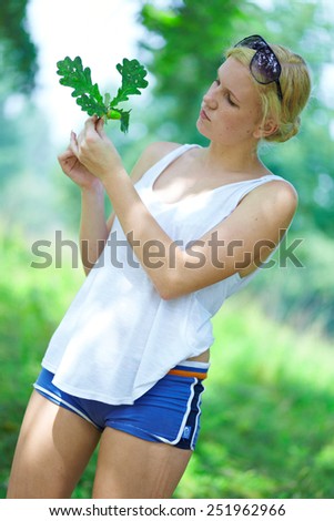 Beautiful girl with oak leaves in hands in the woods