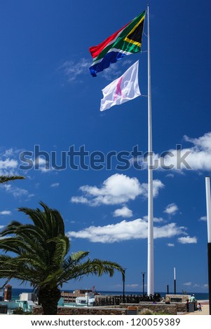 A giant South African flag and a white flag with pink ribbon waving over the city of Port Elizabeth around the famous lighthouse area