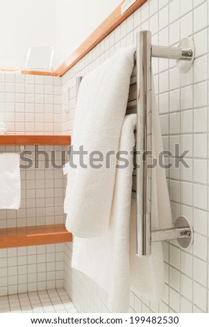 Two white bath towels hanging on a silver towel rack