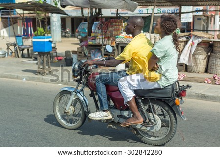 Cotonou, Benin: May 26: A woman rides a hired Motorcycle taxi, the most common means of hired transportation in the city, on May 26, 2015 in Cotonou, Benin.
