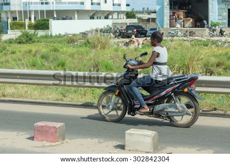 Cotonou, Benin: May 26: A woman rides a Motorcycle, the most common means of  transportation in the city, on May 26, 2015 in Cotonou, Benin.
