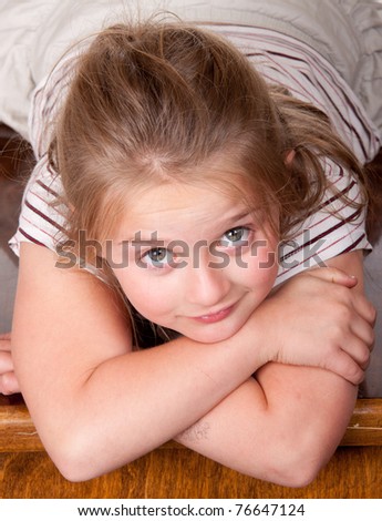 A photograph of a young girl lying on a desk looking up at the world.