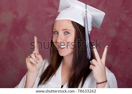 A cute girl poses for her graduation photo.  There is a pink background. She is holding up the number 12 for class of 2012