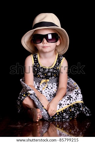 A cool image of a cute little girl wearing a hat and sunglasses.