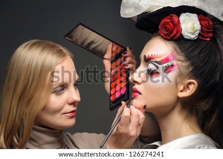 Young model having her makeup done before her shoot, make up master