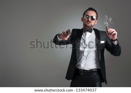 Cool man in a suit with a cigar, gun and glass with alcoholic beverage