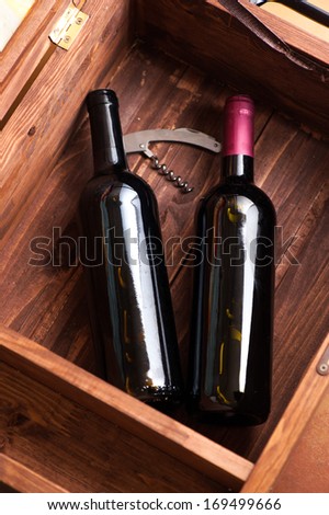 Open wood case with two bottles of red wine inside and corkscrew