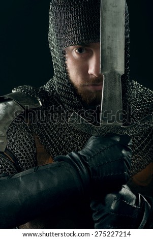 Ancient knight in metal armor with sword in hands