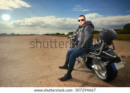 Biker in leather jacket sitting on a motorcycle.