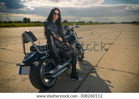 Biker girl in leather jacket sitting on a motorcycle.