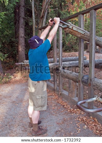 Man exercises with weight lifting device in a park