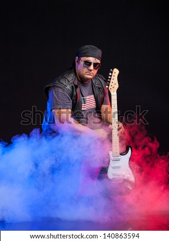 old school rock musician is playing electrical guitar. Shot in a studio.