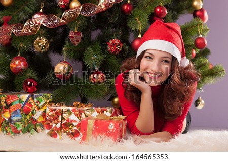 Beautiful girl with a gift near the Christmas tree
