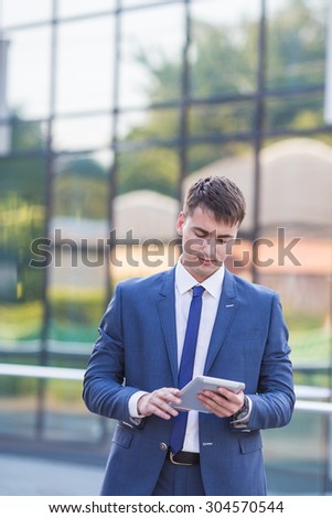 young business man think look up hold tablet pc computer, in bright blue office