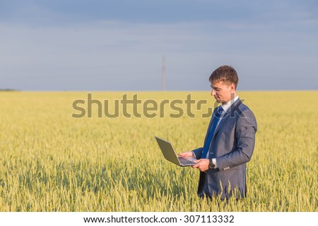 Businessman on a wheat field using a laptop