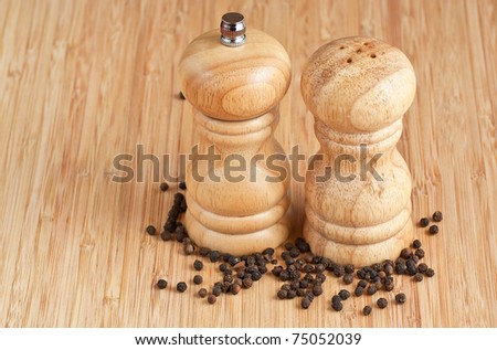 salt and pepper grinders on a table, with pepper spread around