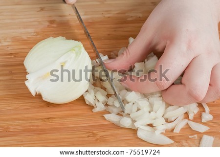 The hands cutting onions on a chopping board