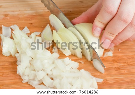 The hands cutting onions on a chopping board