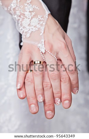 Wedding details - closeup of hands of newly-married with gold rings